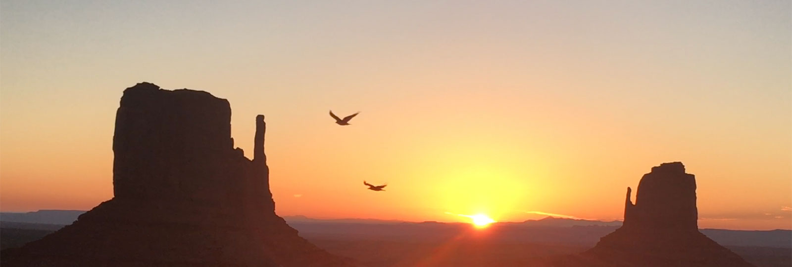 Orange-Yellow Sunrise Between Two Peaks with Birds Soaring